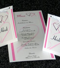 Elegante Schriftrolle als Hochzeitsmenükarte mit rosa Herzen.