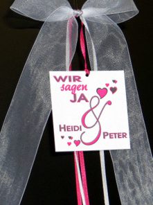 Eine Antenneschleife in tollen Farben wie pink und passendem grau, bedruckt mit einem Herzmotiv und den Namen des Brautpaares