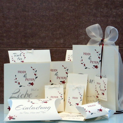 Cremefarbene Hochzeitskarten mit Extras in rot und vielen edlen Schleifen.