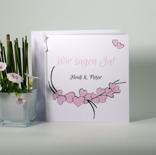 Elegante Hochzeitseinladung mit rosa Herzdesign auf weißen Karton.